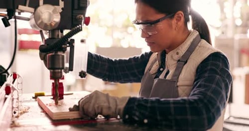 Woman Using Drill Press in Workshop