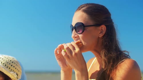Happy hispanic family enjoying a summer picnic eating sandwiches on the beach