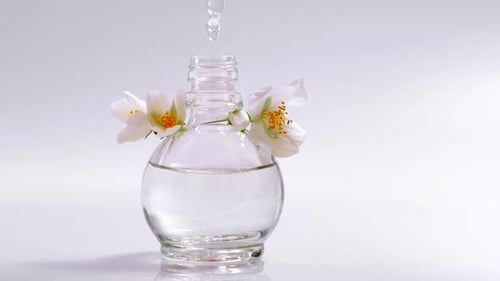 Parfümerie. Tropfen, die von einer Kosmetikpipette auf eine Glasflasche mit Parfümblumenöl fallen