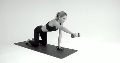 Woman Works Out with Dumbbells on Exercise Mat