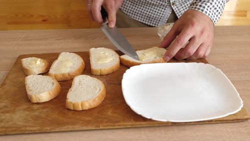 Man Spreads Butter on Bread in Kitchen