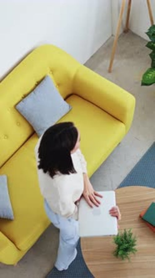 Woman Working on Laptop on Yellow Couch