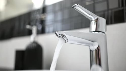 Woman Turns On Modern Faucet Water in Bathroom