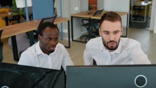 Zwei schockierte gestresste Geschäftsleute sitzen und halten Kopf an Händen am Arbeitsplatz im Büro