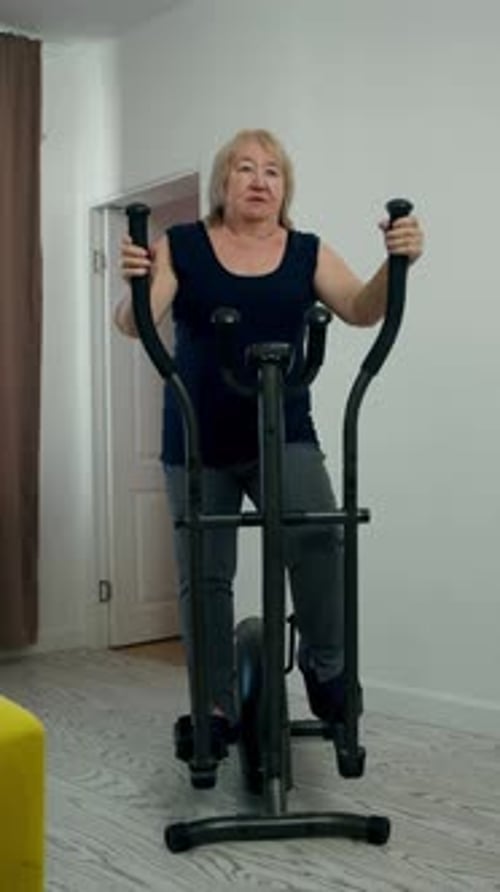 Senior Woman Exercising on Elliptical Machine at Home