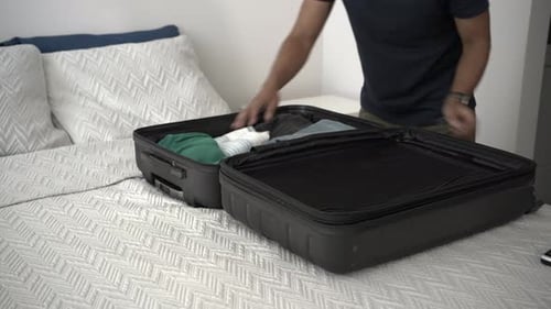 Man Packing a Suitcase on a Bed