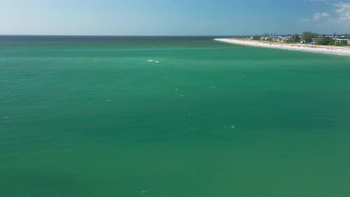 Expansive turquoise ocean with distant shoreline and coastal town — aerial view