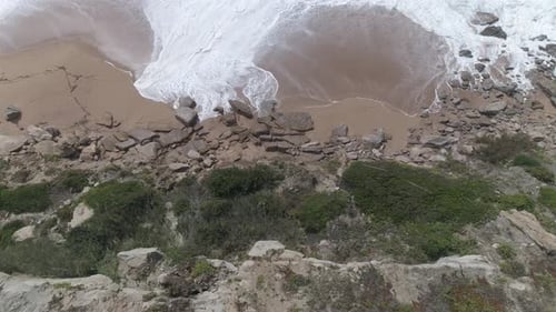 Flight over of rocky coastline. Aerial of Ocean shore, waves crashing cliffs