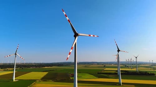 Wind Turbines Spinning in a Green Field on Sunny Day
