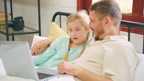 Atractivo padre caucásico usando una computadora portátil con su hija pequeña.
