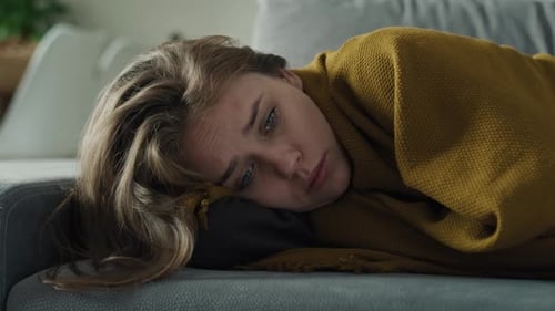 Femme triste caucasienne assise sur le canapé et couvrant la couverture à la maison. Prise de vue avec une caméra à hélium ROUGE