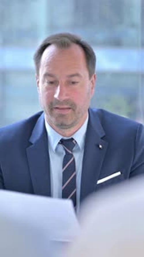 Corporate Man Reviews Documents in Office Meeting