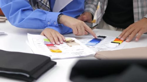 Male Fashion Designer and His Female Assistant Looking at Fabric Samples and Discussing Ideas for