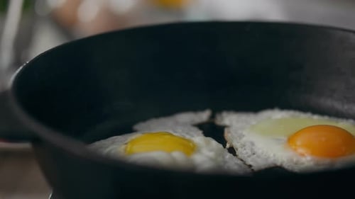 Casserole. Une heureuse femme d'âge moyen vêtue d'un uniforme de chef prépare le petit-déjeuner le matin sur un bois