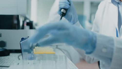 Close-up of the Female Scientist's Hand in Glove Using Micro Pipette while Working with Test Tubes.