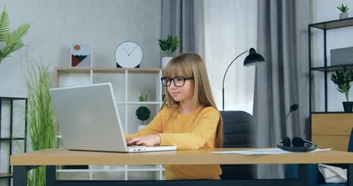 Girl Typing on Laptop at Desk in Home