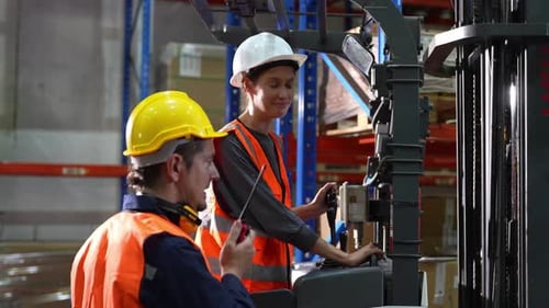 Warehouse worker controlling forklift in warehouse