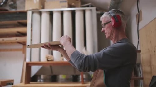 Calgary carpenter inspecting wood piece with precision in his alberta workshop