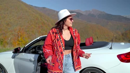 Woman Dances Next to Convertible Car in Mountains