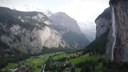 Captivating Drone Shot of Swiss Alp Valley with Towering Waterfall