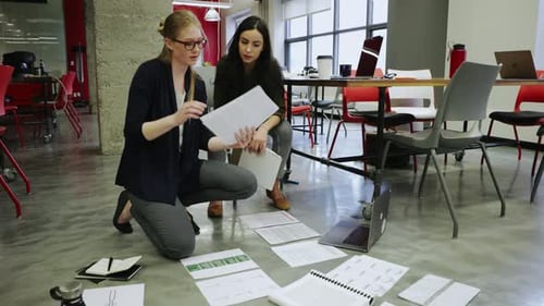 Creative Businesswomen Reviewing Paperwork on Office Floor 2024 Years