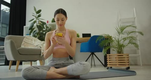 Woman Relaxing After Workout Using Cell Phone