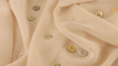 Top view of thin seashell white color chiffon fabric and natural mother-of-pearl buttons