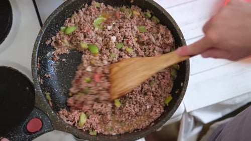Mann, der Sauce für Spaghetti, Bolognese oder Pizza mit einem Holzlöffel in der Pfanne mischt. Flaches, warmes Gericht