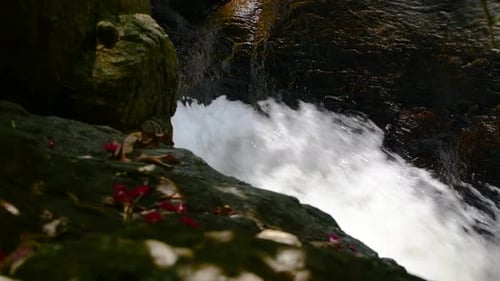 Rapid water splashing in the creek, small yet powerful water stream flowing down fast through rocks.