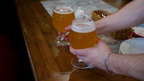 Der Kellner stellt zwei Bierkrüge auf die Tischkante