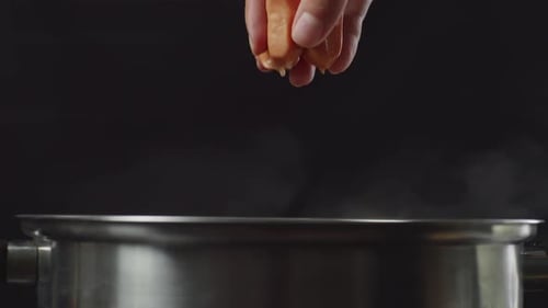 Hand Dropping Sausage into Steaming Pot of Water