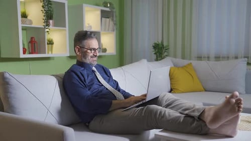 Man Relaxing at Home While Working on Laptop