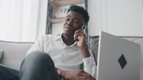 Young Man Working at Home on Couch with Laptop