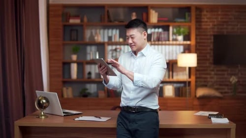 Happy young Asian employee uses a smartphone in the office. Satisfied business man worker texting