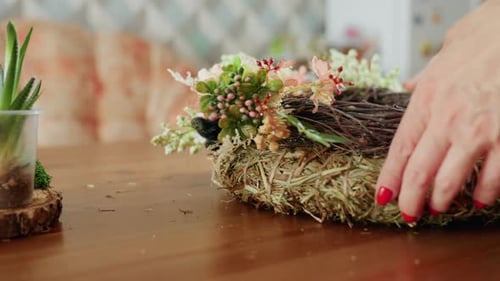 Close Up Female Hand with Red Nails Arranging Handmade Floral Wreath