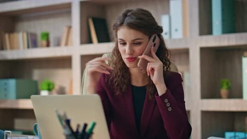 Woman Talking on Phone and Using Laptop in Office