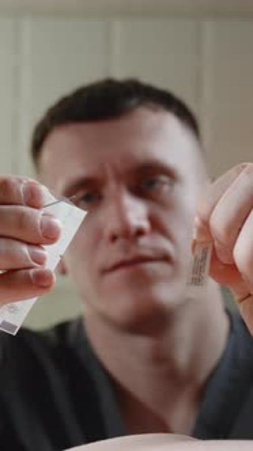 Closeup Sequence of a Man Tearing Open a Small Paper Sachet Then Lifting the Packet Above Hands in