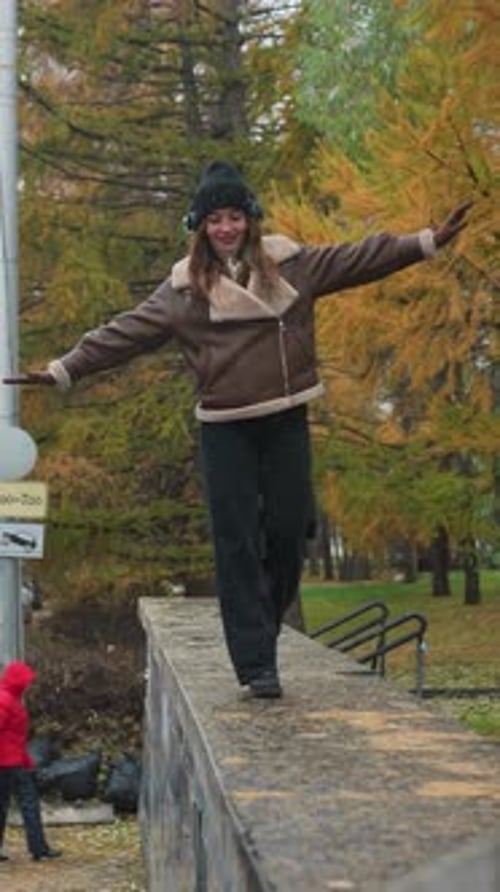 Smiling Girl Walking on Stone Path in Drizzling Rain with Outstretched Arms