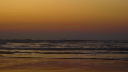 Beautiful relaxing view of ocean waves with an orange sky during the sunset.