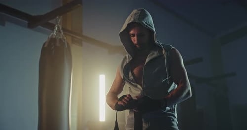Muscular Man Wrapping Hands for Boxing Training