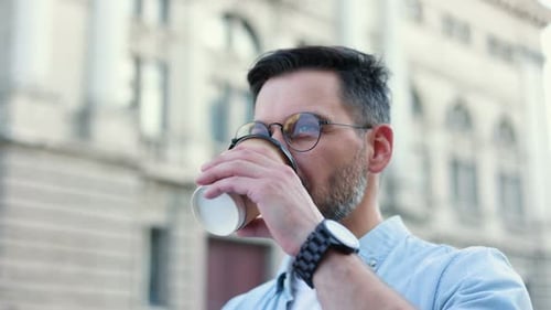 Portrait of Stylish Handsome Caucasian Young Man Walking in the City and Drinking Coffee to Go While