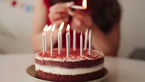 Young Woman Lighting Candles on a Birthday Cake