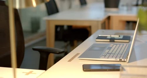 Laptop lid rising in office with camera panning over smartphone and notebook preparing for work