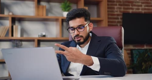 Businessman in formal suit using laptop sitting in his modern office conducts an online lecture