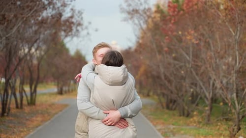 Couple Embrace Joyfully As Man Lifts Wife Sharing Kiss in Autumn Park