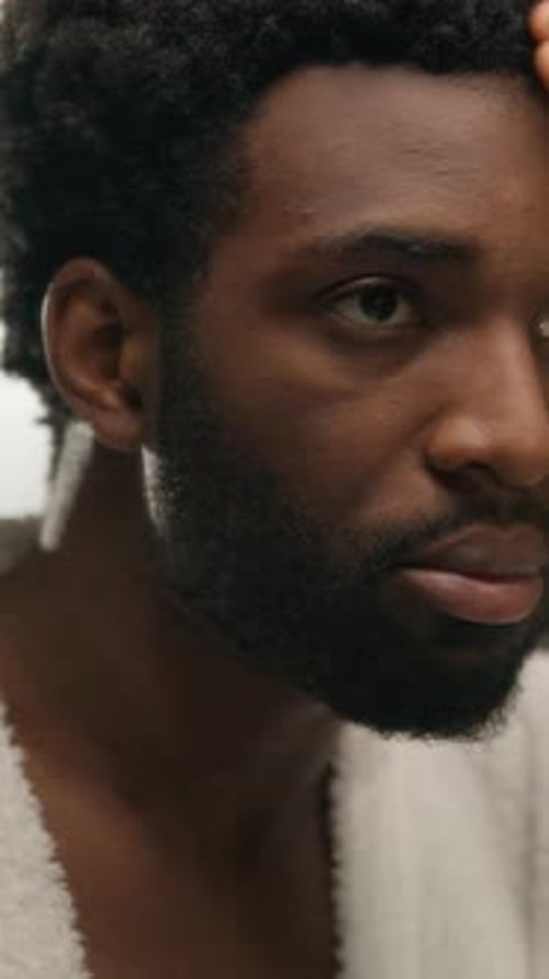 Young Man Applying Lotion to Face and Beard