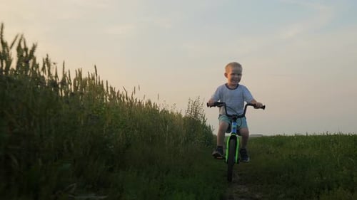 The Boy Learns to Ride a Bike and Rides Towards the Camera