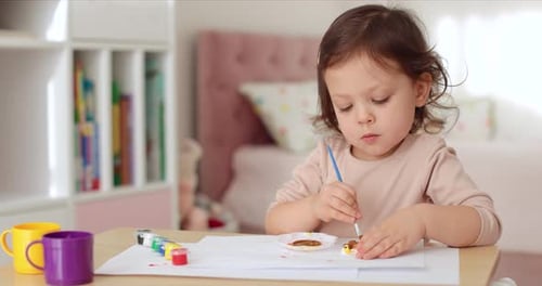 Child Concentrates on Painting at a Table