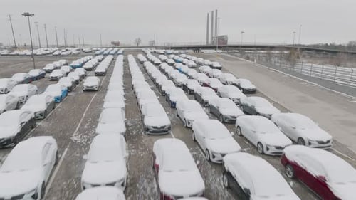 Des voitures couvertes de neige volent à basse altitude et dévoilent une usine d'assemblage de voitures