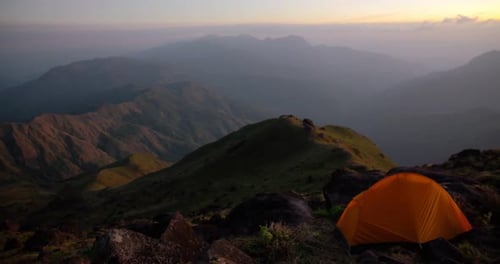 Camping in the mountains with tent on high hill.